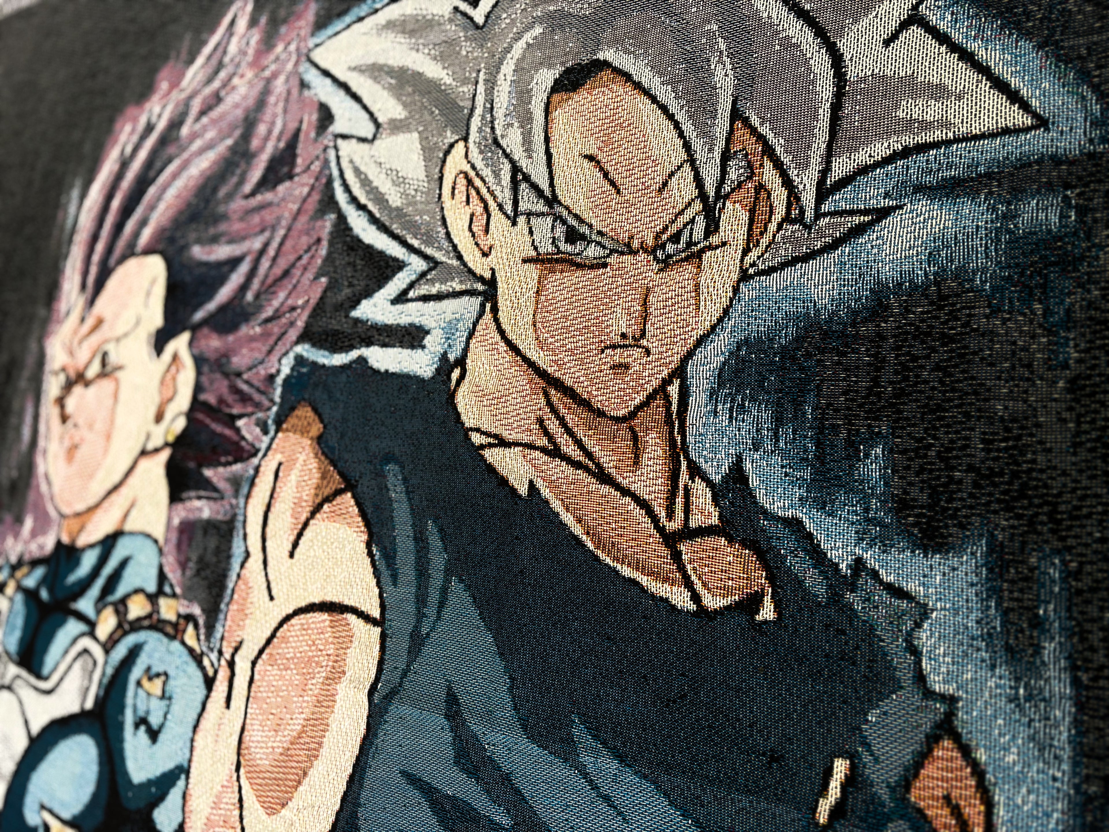 Close-up of a woven or embroidered fabric print featuring anime characters, with a central figure in a black sleeveless top and another character partially visible behind on the left.